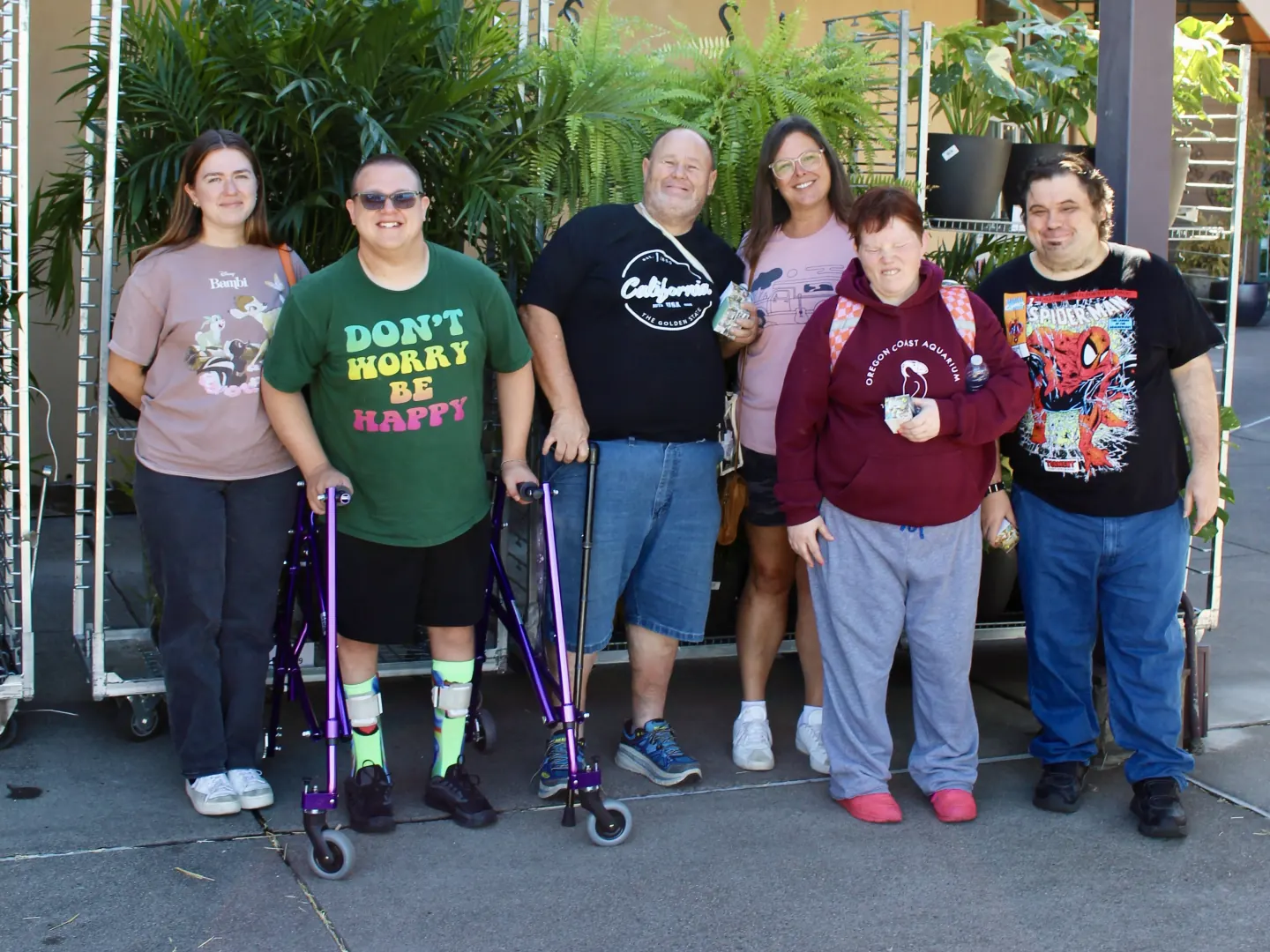 Six people smiling together outside a garden center.