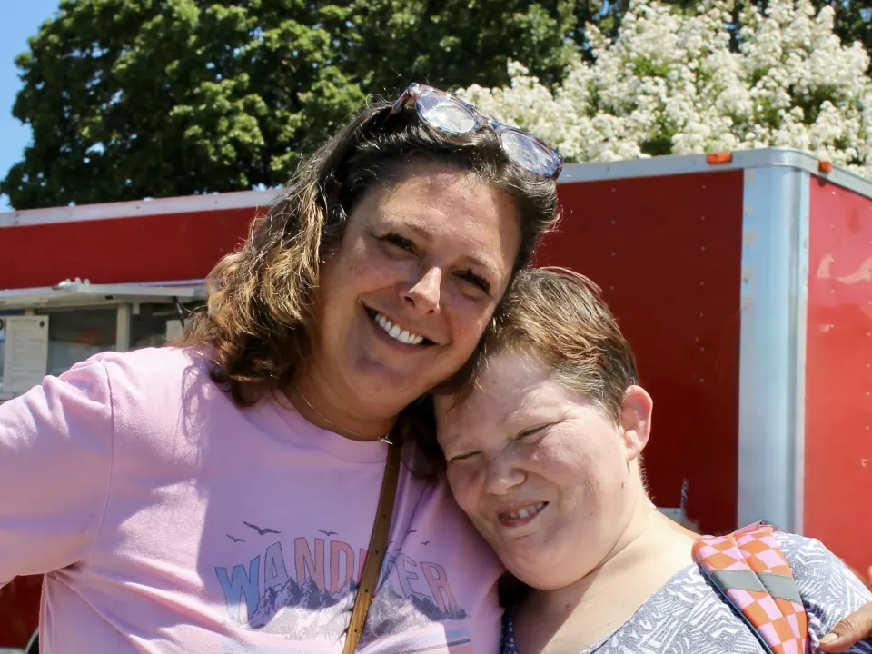 Two people hugging and smiling in the sunshine.
